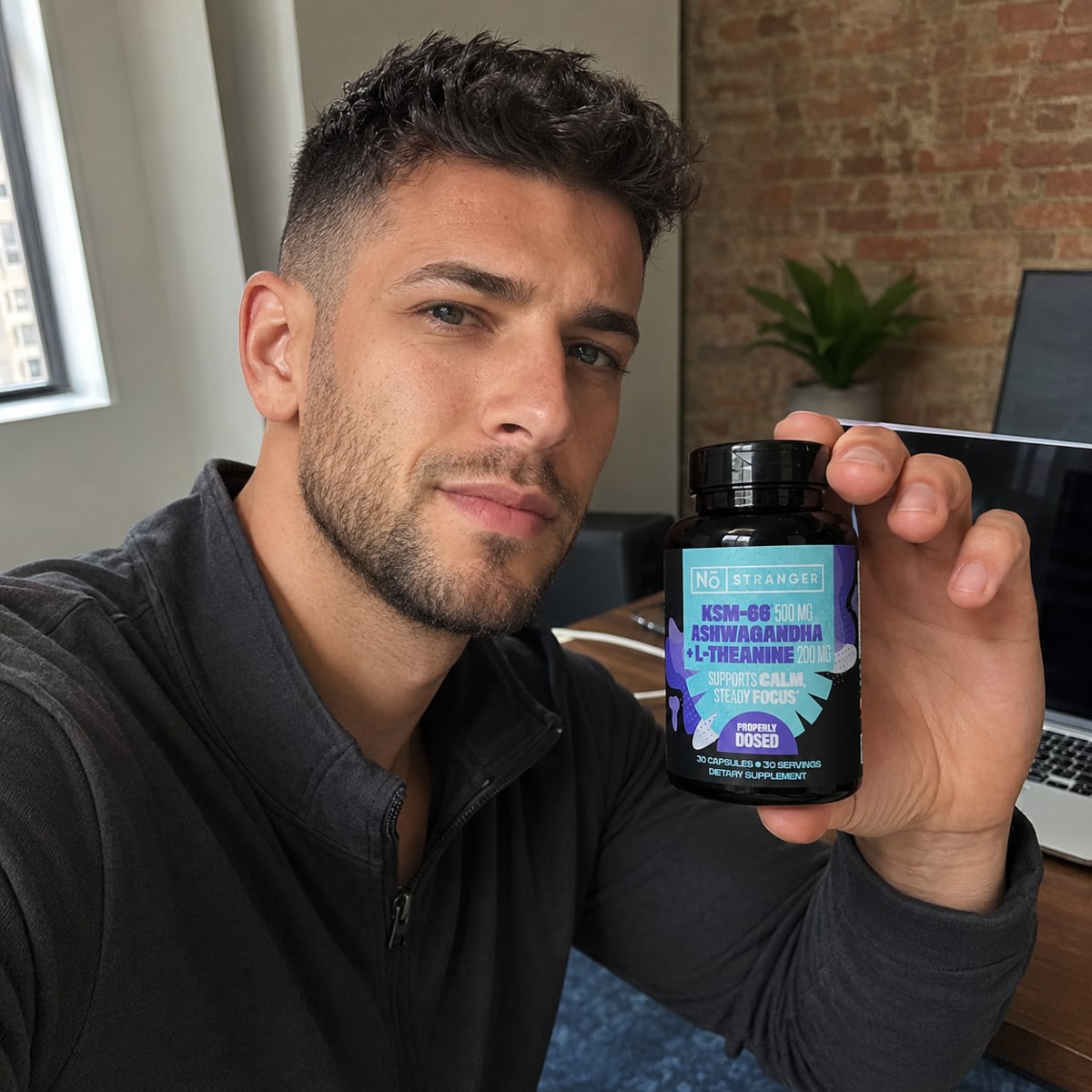 Brian W. holding No Stranger bottle, work-from-home setup